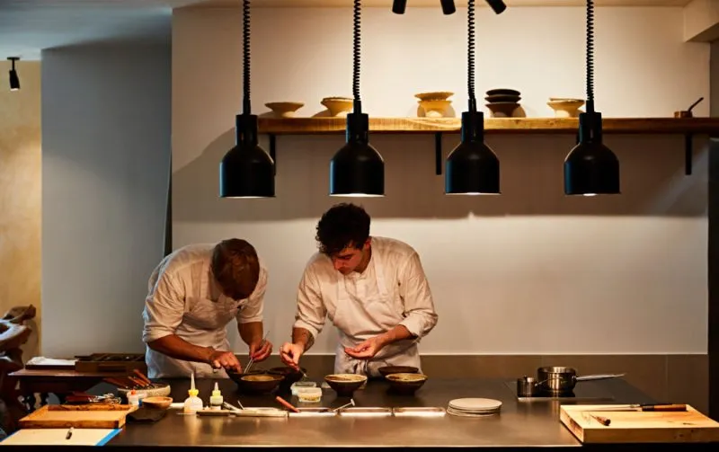 Two chefs prepare dishes in the kitchen of restaurant St. Barts.